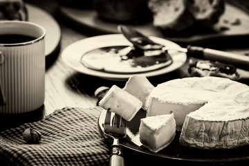 Obraz premium Breakfast in French, in European. Camembert cheese, jam, coffee, olives, fresh pastries and pistachio nuts
