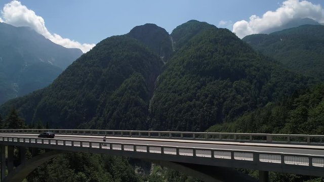 Aerial - Young man longboarding uphill across mountain viaduct in spring