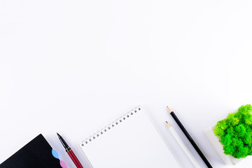 White office desk table with blank notebook, smart phones, headphones and other office supplies. Top view. Copy space. Flat lay.