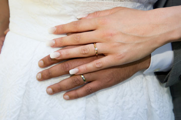 closeup of two hands of caucasian young adults with wedding rings