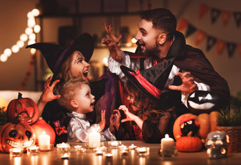 happy family mother father and children in costumes and makeup on  Halloween in dark home