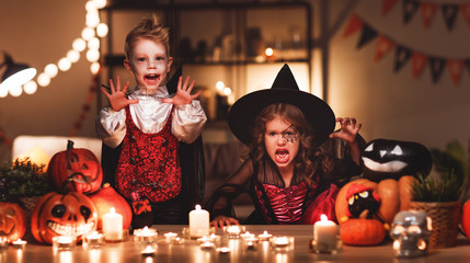 happy children in costumes of witch and vampire in a dark house in halloween