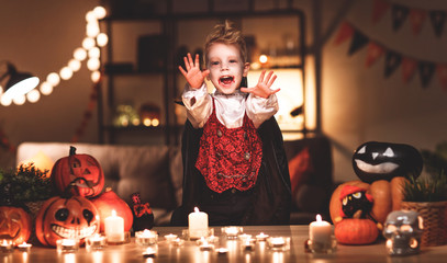 happy child boy in costumes of vampire  in a dark house in halloween