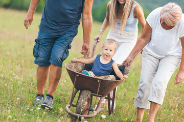 Family pushing their small child in a wheelbarrow