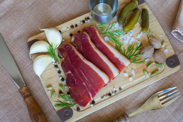 Bavarian jerky with bacon on a wooden Board with pickled cucumbers, vodka and spices