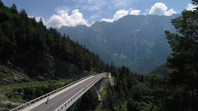 Aerial - Reveal shot of young man longboarding across the mountain viaduct