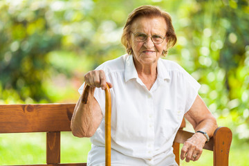 Elderly woman sitting and relaxing on a bench in park