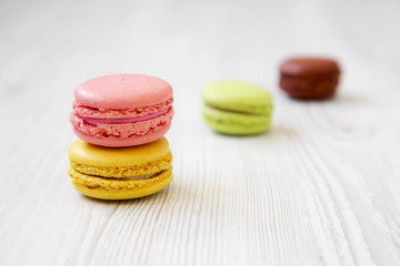 Colorful macarons on a white wooden background, side view. Selective focus.