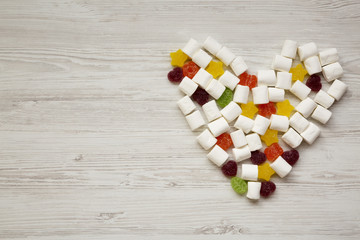 Heart made of candies over white wooden background, top view. From above, flat lay, overhead. Copy...