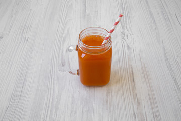 Carrot smoothie on white wooden background, low angle view.