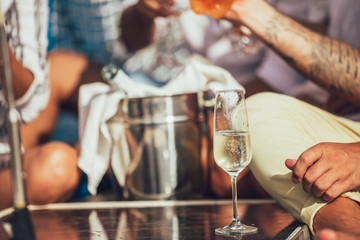 Happy friends with glasses of champagne on yacht. Vacation, travel, sea and friendship concept. Closeup.