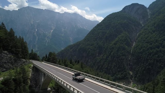 Aerial - Small truck driving across the mountain viaduct in spring
