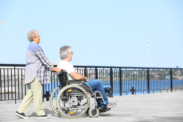 Senior man in wheelchair and his wife outdoors