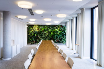 Living green wall, vertical garden indoors with flowers and plants under artificial lighting in meeting boardroom, modern office building - Powered by Adobe