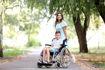 Fototapeta na wymiar Teenage boy in wheelchair with his mother outdoors