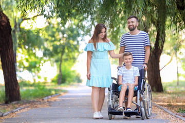 Teenage boy in wheelchair with his family walking outdoors