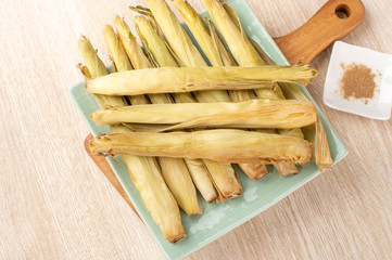 Delicious homemade izakaya-like roast baby corn in wooden background, Taiwan delicacies, top view, copy space