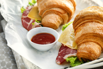 Tasty croissant sandwiches with sauce on tray, closeup