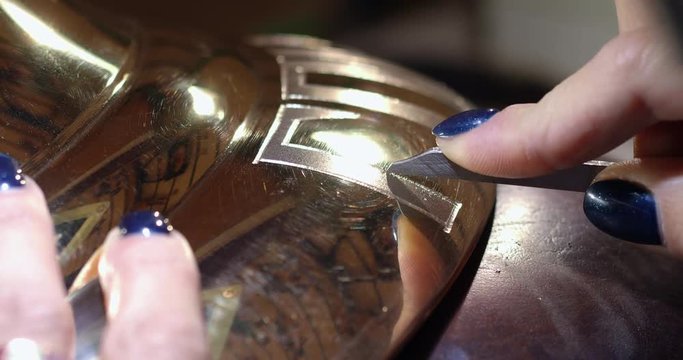 Engraving burin on the bell. Woman engraver, stabs engraving on the bell.