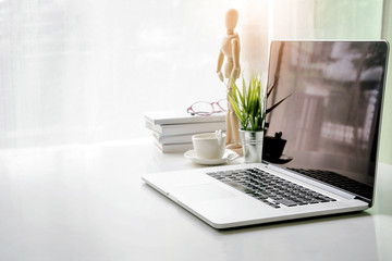 Mockup blank screen laptop with copy space and office supplies on white desk