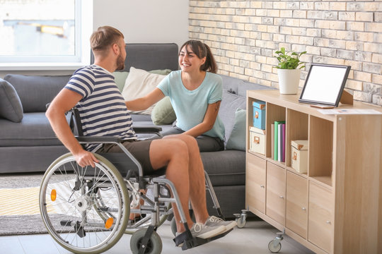 Young man in wheelchair and his wife at home