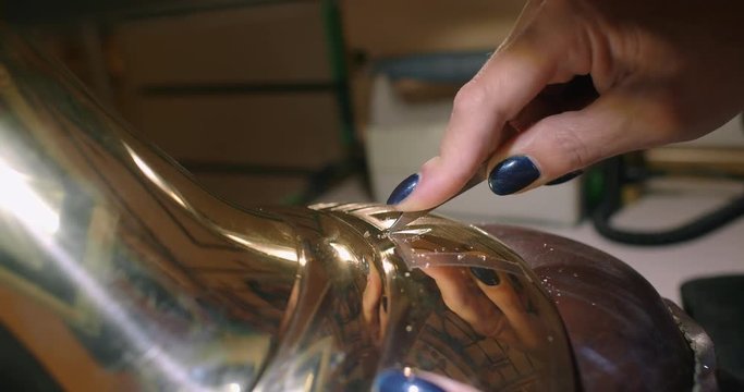Engraving burin on the bell. Woman engraver, stabs engraving on the bell.