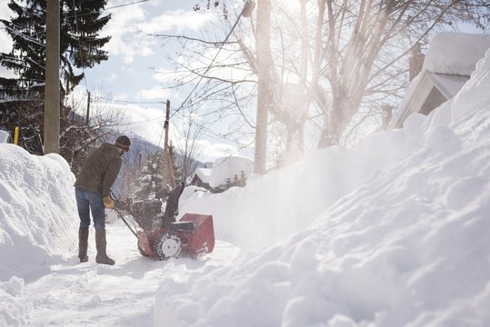 Man using snow blower machine in snowy region