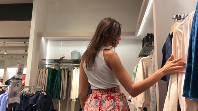 young beautiful emotional modern woman walks through the shopping center, looks at fashion things in clothing stores