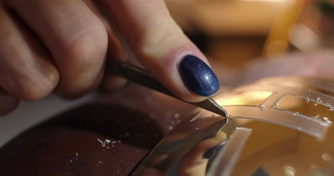 Engraving burin on the bell. Woman engraver, stabs engraving on the bell.