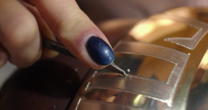 Engraving burin on the bell. Woman engraver, stabs engraving on the bell.