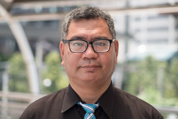 Fototapeta premium old south east asian business man face; face portrait of old senior southeast asian businessman, formal office worker with eye glasses and grey hair; south east asian middle age to senior man model