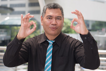 ok hand sign from successful old business man; portrait of happy, strong, successful southeast...
