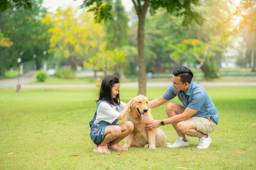 Fototapeta premium Brother and sister petting the lovely golden retriever dog in the garden