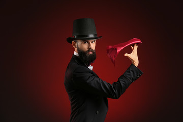 Magician showing tricks on dark background