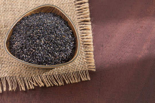 Black organic seeds of sesame - Sesamum indicum. Wood background