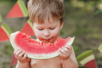 Baby blond boy eat watermelon and smile. Child has healthy eating habits