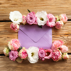 Beautiful flowers with envelope on wooden background