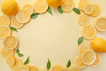 Frame made of lemon slices and green leaves on color background