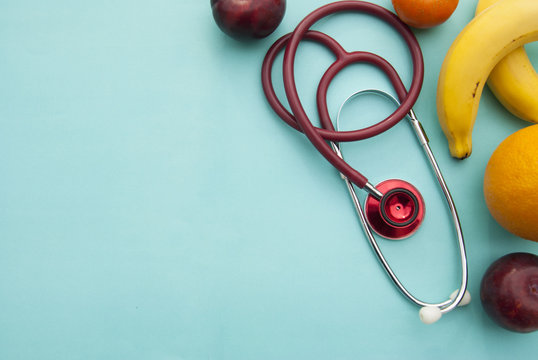 Medicine and healthcare, nutrition or medical insurance over blue background. Fruits and red sthetoscop. Copy space. - Powered by Adobe