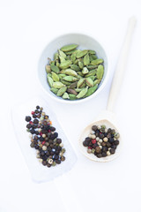 Dry spices and herbs in glass jar with a cork, a bowl of cherry tomatoes and chili peppers, white background