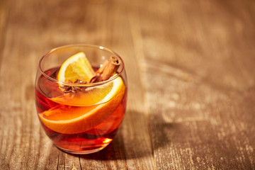 close up view of hot mulled wine drink with orange pieces and anise stars on wooden surface