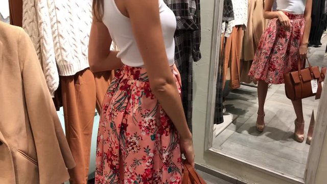 modern woman walks through the shopping center, looks at fashion things in clothing stores