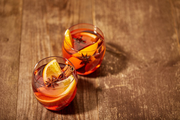 close up view of delicious hot mulled wine drinks with orange pieces on wooden tabletop