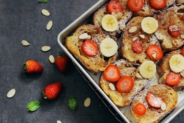 Overnight baked French toast topped with berries bananaa and nuts, overhead view