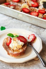 Breakfast baked french Toast served in a plate topped with berries nuts and banana, top view
