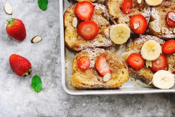 Overnight baked French toast topped with berries bananaa and nuts, overhead view