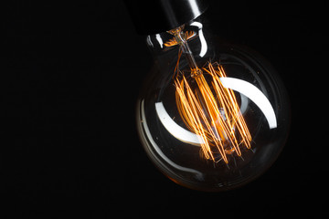 A classic Edison light bulb on dark background with space for text