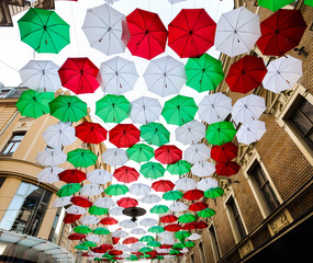 Fototapeta na wymiar A lot of red white and green umbrellas hanging above the street