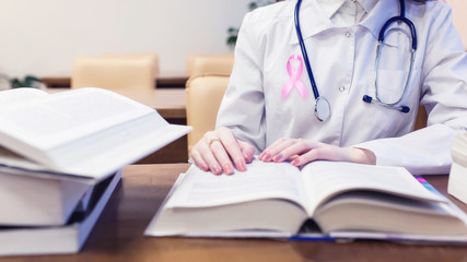 Female doctor with pink ribbon, medical student for textbooks. Protocols for diagnosis and treatment of breast cancer.