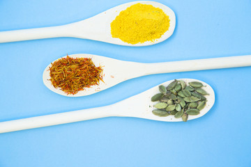 Cooking Hot Spicy Food Concept. Dry spices and herbs in wooden spoons, light blue background